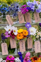 Glass jars and bottles filled with cut flowers grown in the garden. Pictured from left to right - love-in-the mist, sea holly, statice, sweet pea, lavender, cosmos, marigold, scabious, feverfew.