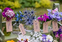 Glass jars and bottles filled with cut flowers grown in the garden. Pictured from left to right - sweet  William, love-in-the-mist, sea holly, statice and sweet pea.