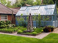 Greenhouse behind potager of four raised beds of strawberries, fruit trees and herbs - chives, sage, chamomile, fennel. Tulipa 'White Triumphator' and 'Spring Green'.