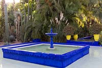 Blue fountain and pool with palm trees and cacti at Jardin Majorelle, Yves Saint Laurent garden 