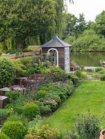Riverside garden by Andy Sturgeon. Left bed - oak cubes, allium, erysimum, Hebe vernicosa, box, iris, aquilegia, fern, nandina, mahonia