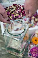 Making potpourri step by step. The mixture of fragranced orris root and the dried flowers and petals are then stored in an air tight glass jar.