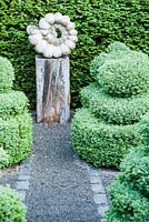 Ammonite sculpture by Darren Yeadon surrounded by box topiary, set within yew hedges. 