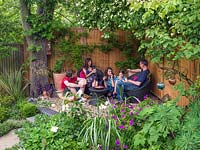The Monaghan family relax in a shady seating area at the bottom of their modern town garden, Muswell Hill, London.