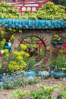 Oriental raku-tiled mirrored wall by artist owner, with pots of tulips, self-seeded forget-me-not and euphorbia.