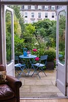 View from the house to a patio seating area in a densely planted town garden.
