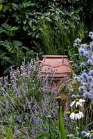 A terracotta urn hidden amongst a white and purple border with Echinacea, Eryngium and lavender.
