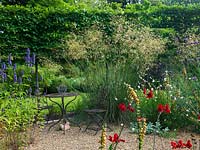 A seating area and gravel garden planted with Crocosmia, Agastache, Gaura lindheimeri, Verbena bonariensis and Stipa gigantea 'Gold Fontaene'. Backed by pleached hornbeam hedge.