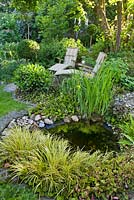 Relaxing area in shady garden. Small pond.