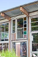Shed built with old wooden window frames in the front. Roof made of corrugated metal.  
