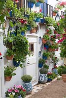 An Andalusian Moment, Best Show Garden, Malvern Spring Gardening Show 2015. Colourful pelargoniums in pots on the white washed walls around a doorway