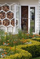 The Bees Knees garden in support of the Bumblebee Conservation Trust, Malvern Spring Gardening Show 2015. Hive shaped wood store and box hedging, and plants for pollinators such as orange Geum 'Totally Tangerine'