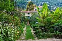 Grass pathway leads to villa through wide flower borders of front garden