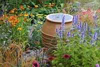 Terracotta pot water feature in colourful flowerbed