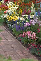 Bright flower border fronted by brick pathway