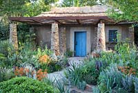small house with thatched roof, mixed herbaceous border with Erysimum 'Apricot Twist' - Sentebale - Hope in Vulnerability 