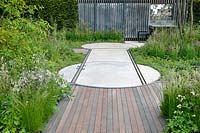 Decking, rails for moveable shack, wall and mixed herbaceous borders of grasses and flowers. The Cloudy Bay and Bord na Mona garden, Chelsea Flower Show 2015

