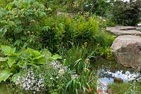 Naturalistic recreation of Trout stream and Paxton's rockery. Rocky pool with Iris 'Berlin Tiger'.  The Laurent-Perrier Chatsworth Garden. RHS Chelsea Flower Show, 2015