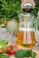 Adding Pimm's to a jug of lemonade, ingredients in foreground