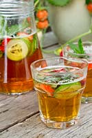 Two drinks of Pimm's and lemonade with Mint, Cucumber and Strawberries added to the jug