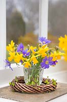 Narcissus and Anemone in a glass jar within woven willow wreath