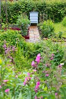 Garden wildflower area with reclaimed pamment pathway leading to traditional beehive