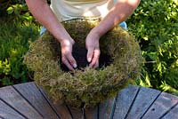 Filling the base of hanging basket with compost