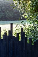 Black painted wooden fence with irregular profile. June 2015. 