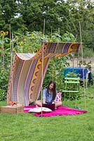 Young girl using a laptop in a sun canopy created with fabric and minimal materials
