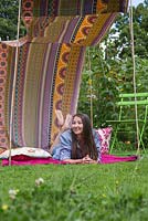 Young girl relaxing in a sun canopy created with fabric and minimal materials