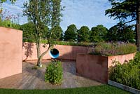 Pink painted raised bed with slope planted with perennials surrounding cork oak surface in contemplative space. SABO - The Circle of Life, Sponsor - Sabo Oil.  Silver-gilt medal, RHS Hampton Court Palace Flower Show 2015