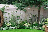 Soft white planting along timber wall. Bird nests, bee station and seed feeders - Living Landscapes 'City Twitchers' garden, RHS Hampton Court Flower Show 2015