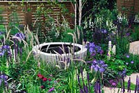 Stone pond-in-a-pot water feature set in a flower bed - The Wellbeing of Women Garden, RHS Hampton Court Palace Flower Show 2015 