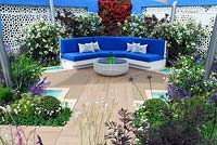 Mediterranean style garden, built-in blue bench with cushions, white aluminium panels set in painted walls. Vertical living wall of bougainvillea, white Oleander shrubs - Spirit of the Aegean, RHS Hampton court Palace Flower show 2015