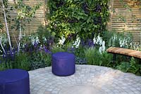 The Wellbeing of Women Garden - purple cushion seat on stone paved patio with wooden bench and fence, living wall planted with Heuchera 'Obsidian', Athyrium filix-femina, berbaceous border planting of Digitalis 'Camelot White', Salvia officinalis 'Purpurascens', Salvia nemorosa 'Caradonna', Pennisetum orientalis, Verbena rigida - Designed by Wendy von Buren, Claire Moreno, Amy Robertson - Sponsors Tattersall Landscapes, London Stone, Jacksons Fencing, Hedgeworx, Tactile Studios - RHS Hampton Court Flower Show 2015 - awarded Silver gilt