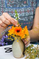 Herbs and edibles posie step by step in August. Stripping stems of basil flowers free of the leaves, before inserting amidst the fennel flowers and nasturtiums.