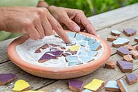 Pushing Mosaic pieces into adhesive