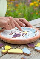 Pushing Mosaic pieces into adhesive
