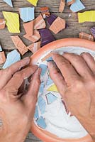 Pushing mosaic pieces into adhesive