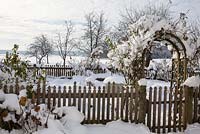 Winter scene with farmer's garden surrounded by a wooden fence