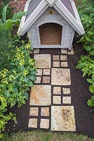 York stone slab path filled in with soil, leading up to dog kennel