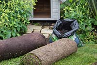 A roll of garden lawn turf, compost and sedum matting
