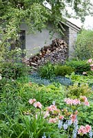 Log pile next to Spring garden with Azalea 'Delicatissima' and Veronica gentianoides in foreground, Myosotis and Hosta behind - Westbrook House, Somerset