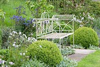 White metal bench surrounded by clipped Buxus balls, Stachys byzantina, Aquilegia vulgaris and Polemonium - Westbrook House, Somerset