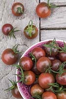 Bowl of Tomato 'Chocolate Cherry' - Lycopersicon lycopersicum on wooden table