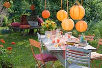 Garden decorated for party with orange lanterns as decoration: Bouquet of calendula, Helenium and Alchemilla 
