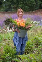 Sheree King holding a bucket of Lupins, Panicum violaceum, Dahlias and Panicum elegans 'Frosted Explosion'