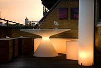 Contemporary balcony overlooking the Thames at Wapping with illuminated white plastic dining furniture in small space 
