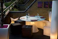 Contemporary balcony overlooking the Thames at Wapping with lit white plastic dining furniture 
