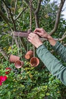 Tying empty terracotta pots to the weathered wheel with string